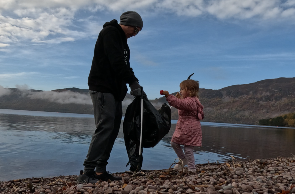 AtlasAdventured family picking up trash on the beach at Loch Ness, Scotland. Sustainable travel