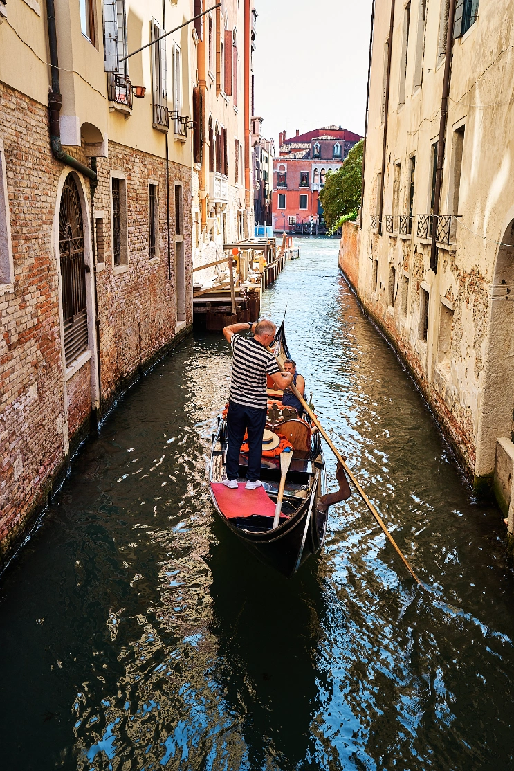 gondolier on his gondola in canal in venice, italy